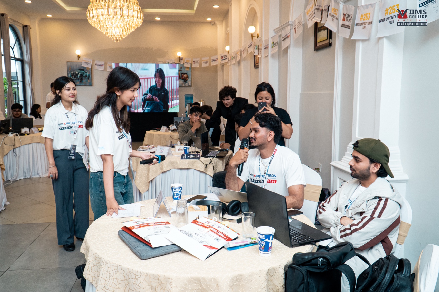 A participant speaking into a microphone during an informal check-in on the hackathon floor