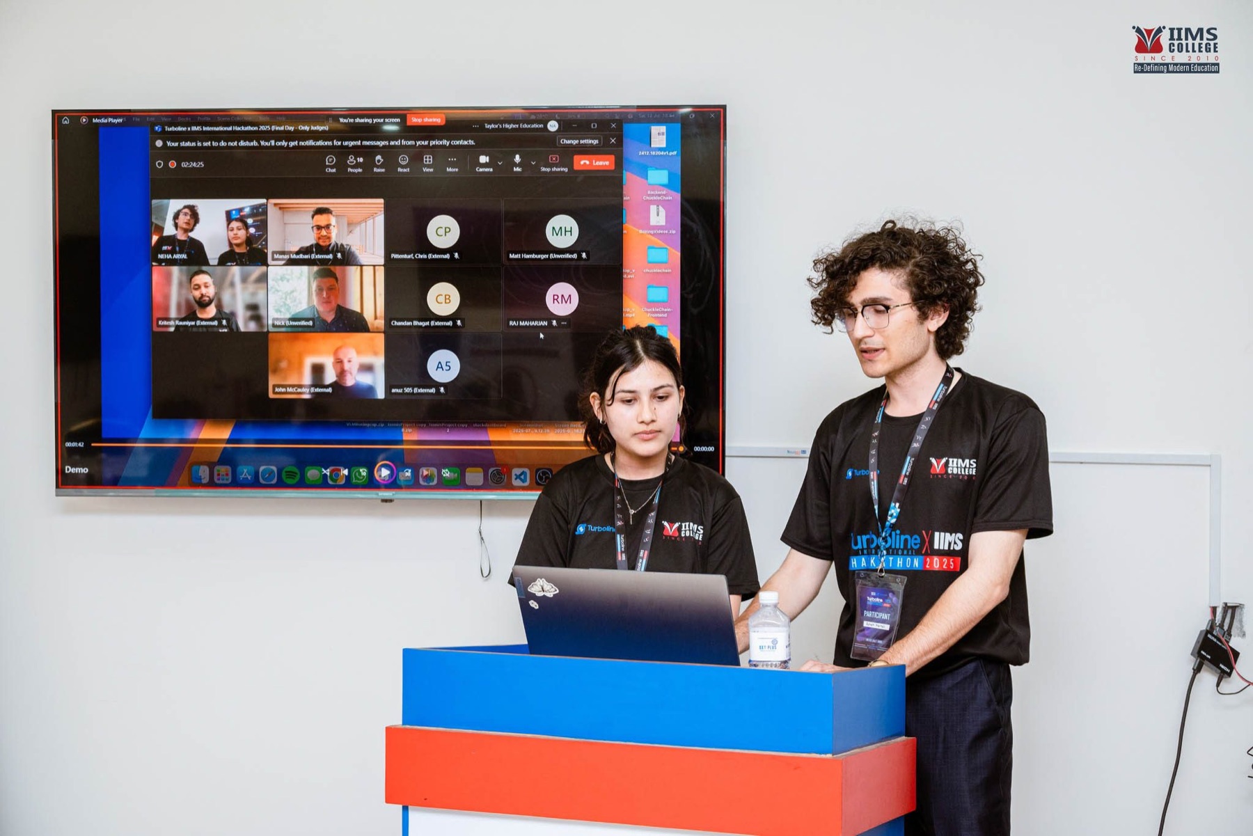 A team presenting alongside virtual participants shown on a video call
